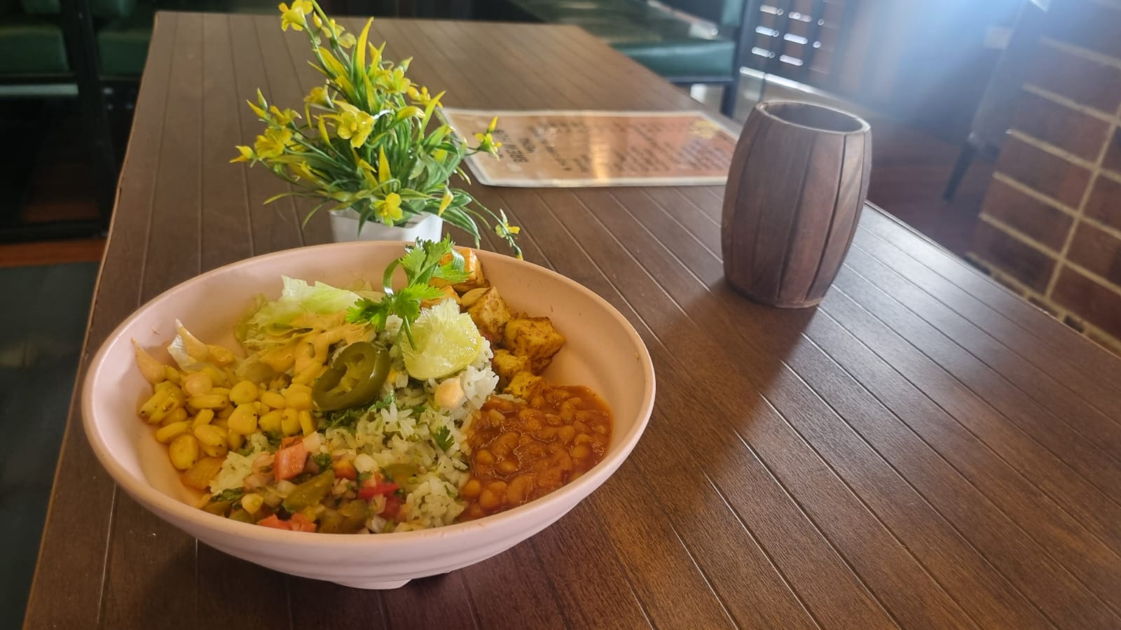 Colorful Mexican rice bowl with vegetables, beans, salsa, and cheese.