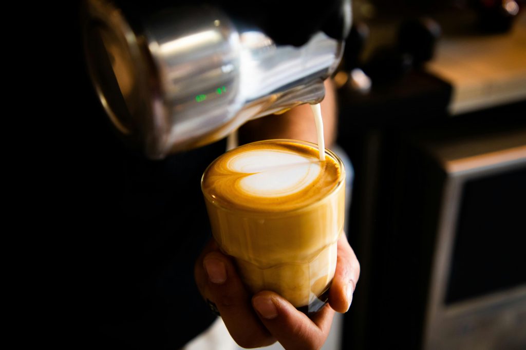 Close-up of barista creating heart-shaped latte art in a cozy Amman cafe.