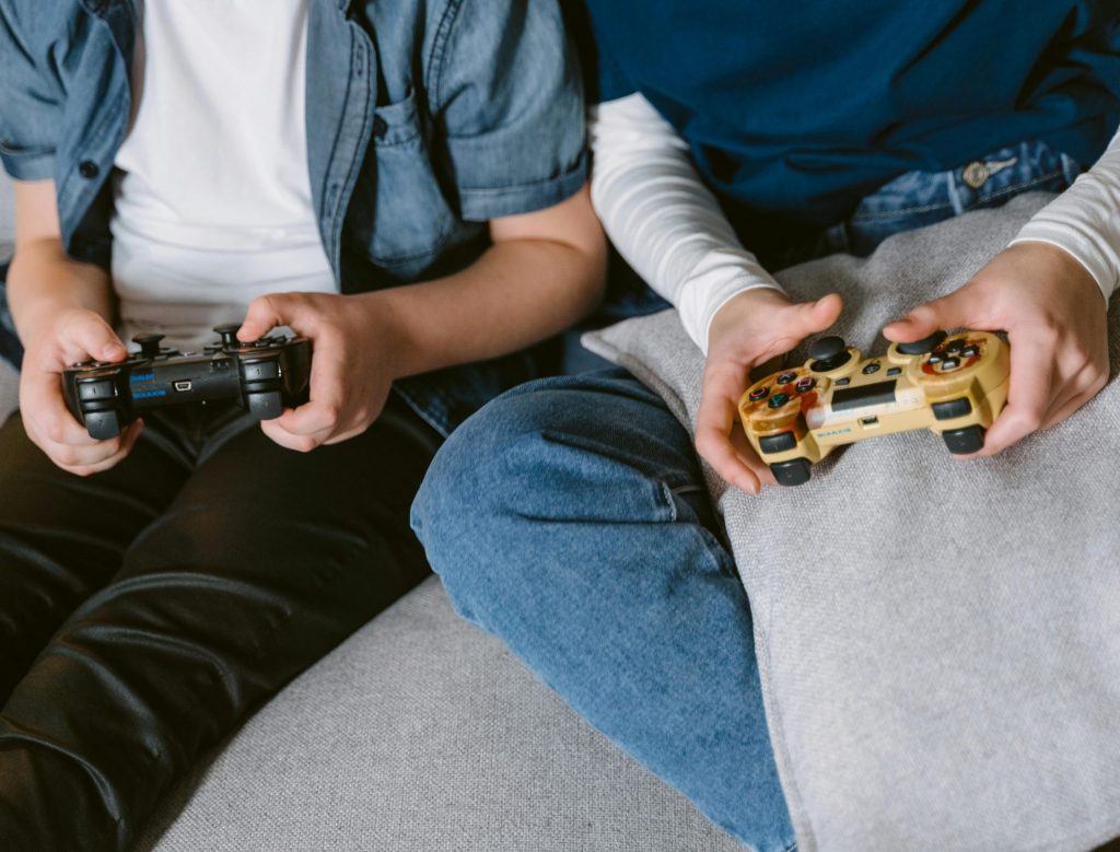 Two teenagers absorbed in console gaming indoors, focused on controllers.